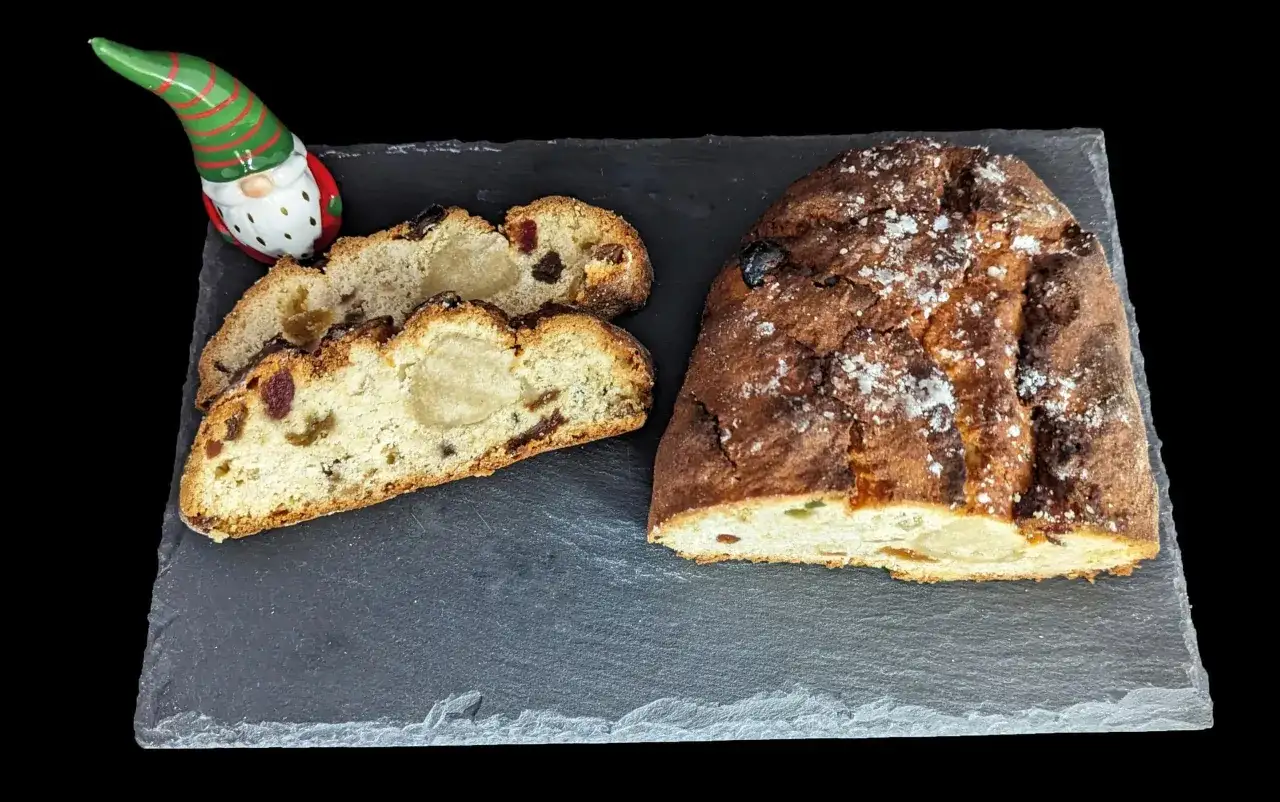 Un stollen cake, saucisson de No&euml;l, coup&eacute; en tranches, avec une figurine de lutin.