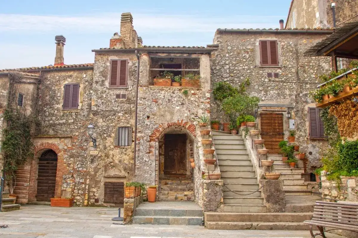Antica piazza con case in pietra e scale fiorite, un'immagine di borghi vicino Livorno.