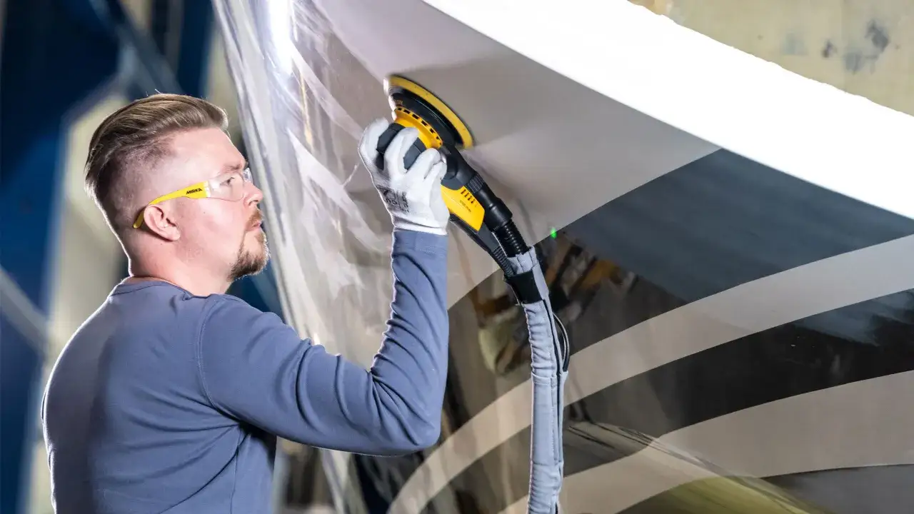 Man polerar en båt med en polermaskin. Menzerna gelcoat premium one step polish ger en perfekt finish.