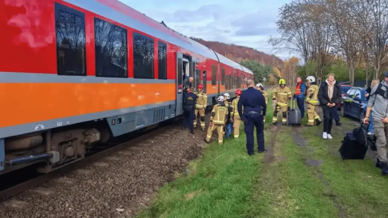 Strażacy i policjanci pomagają pasażerom po wykolejeniu pociągu.