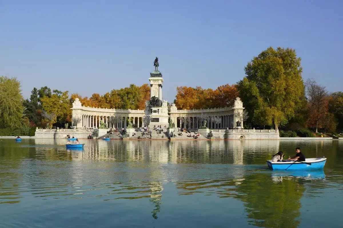 Boote auf dem See im Retiro Park, mit dem Monument Alfonso XII im Hintergrund und bunten Herbstb&auml;umen.