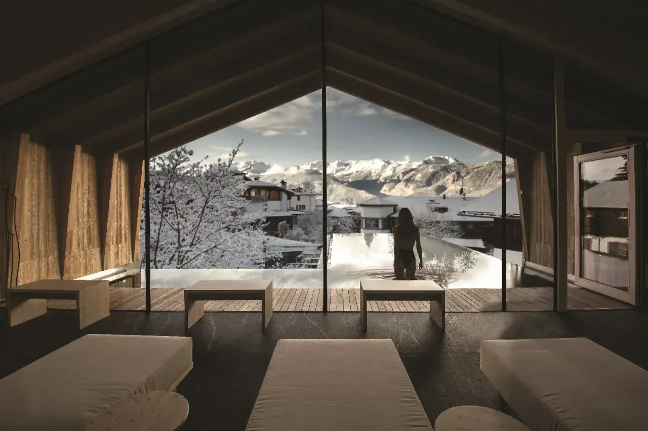 Interno di un resort di lusso con piscina a sfioro e vista sulle montagne innevate. Un'oasi di pace nel **pineta nature resort**.