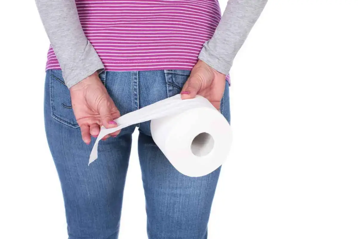 Person med jeans och randig tröja håller en toalettrulle. Kan vara relaterat till hemorrojder blod.