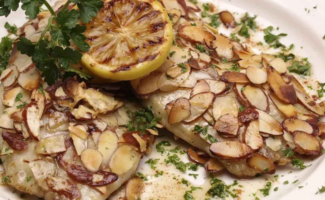 Délicieuse truite aux amandes au four, garnie d'une tranche de citron grillée et de persil frais. Un plat savoureux et croustillant.
