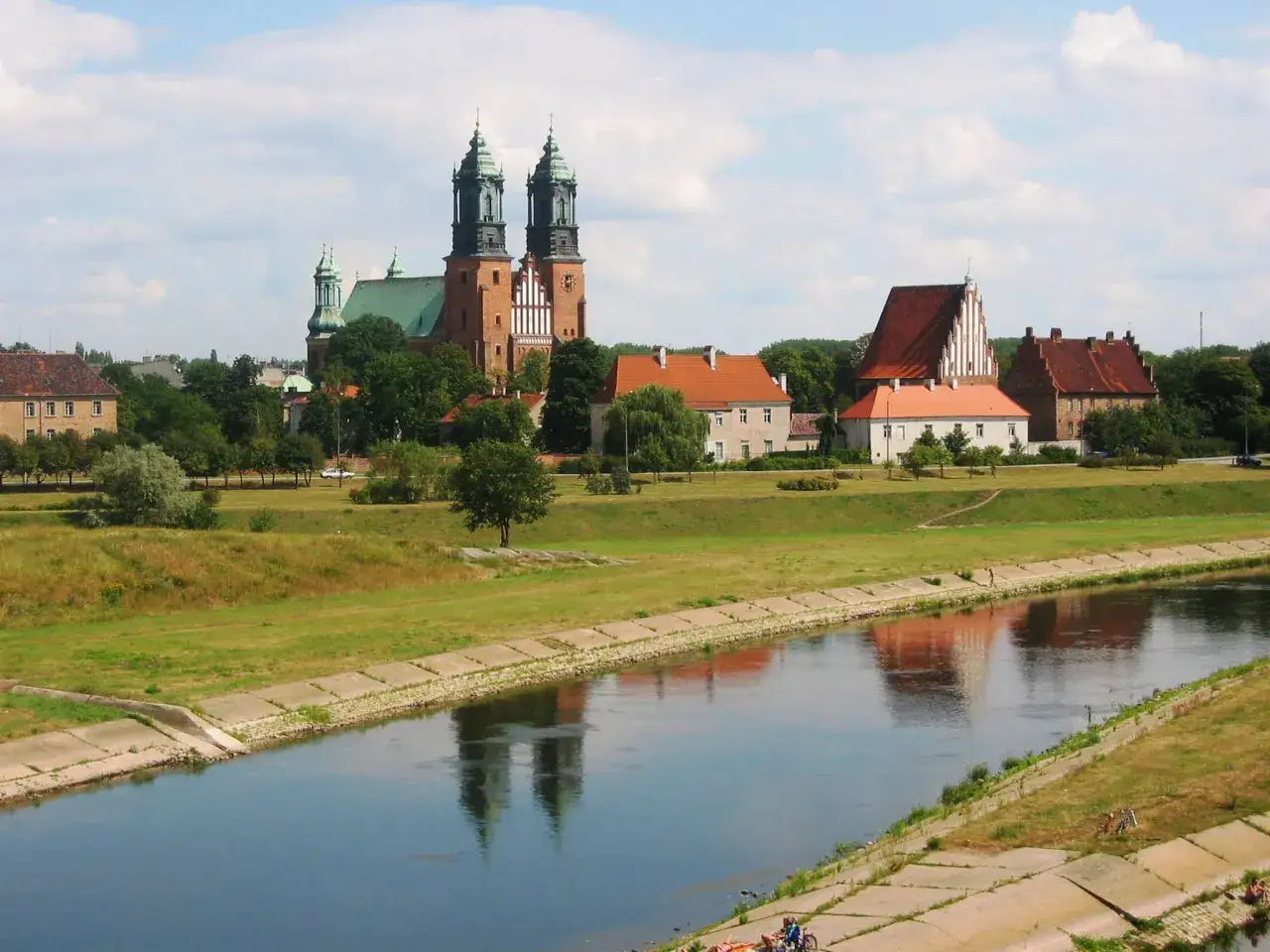 Flussufer mit Blick auf die Kathedrale von Posen, Polen. Die T&uuml;rme spiegeln sich im Wasser.