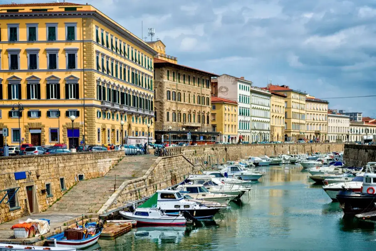 Bateaux amarrés dans un canal bordé de bâtiments colorés à Livourne, Italie.