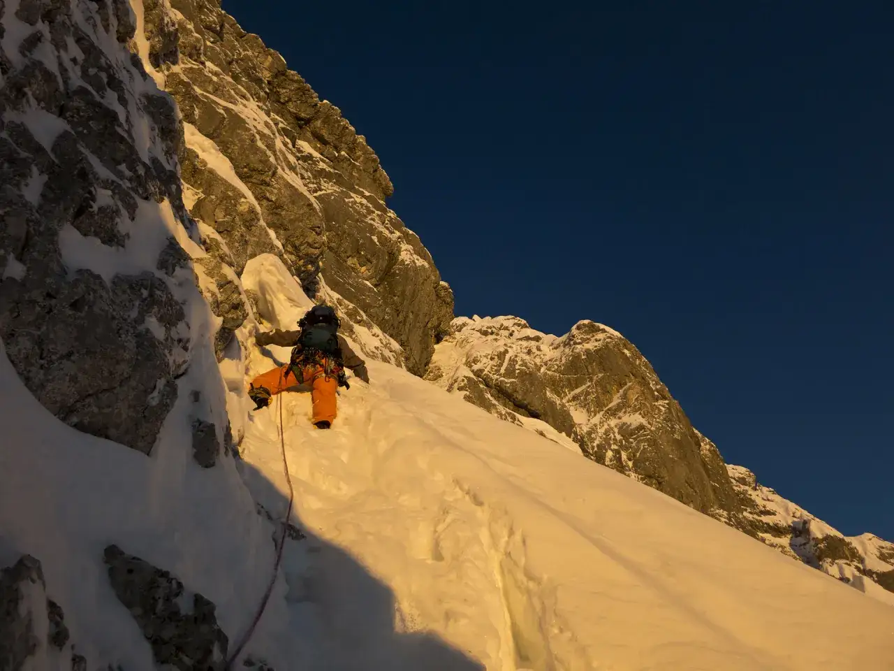 Bergsteiger klettert die Watzmann Ostwand im warmen Abendlicht empor.