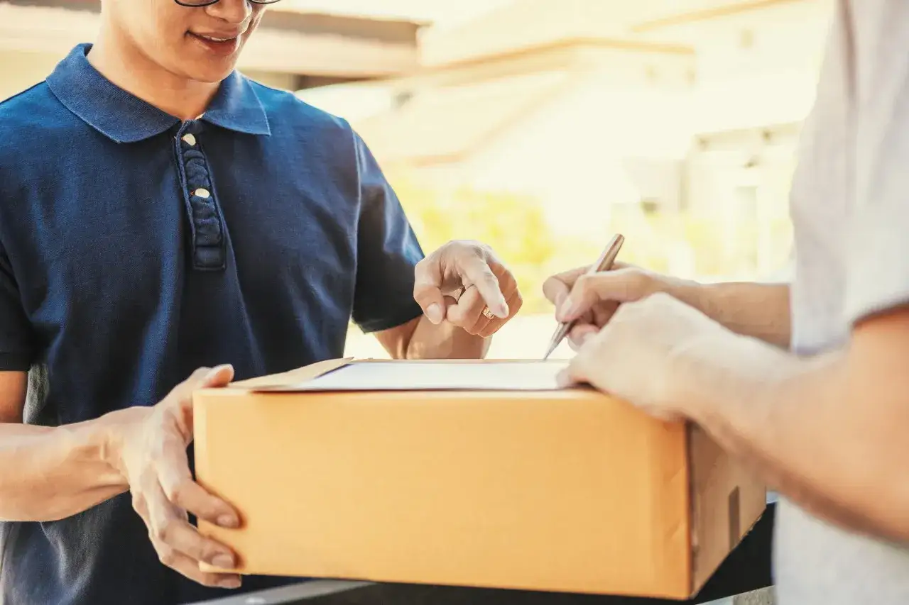Livraison d'un colis. Le livreur pointe un document, le client signe, peut-être pour signaler un produit non conforme à la commande.