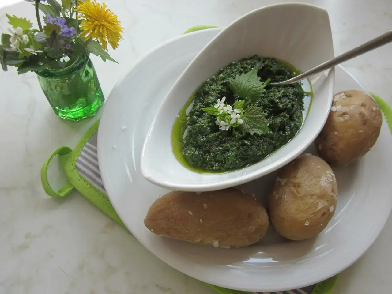 Frisches mojo verde mit Kr&auml;utern und kleinen wei&szlig;en Bl&uuml;ten, serviert mit Salzkartoffeln. Ein kleiner Strau&szlig; Wildblumen steht daneben.