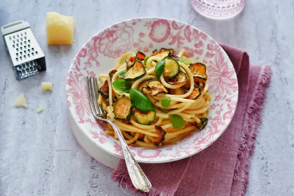 Spaghetti alla Nerano con zucchine fritte e basilico fresco, un piatto estivo da gustare.