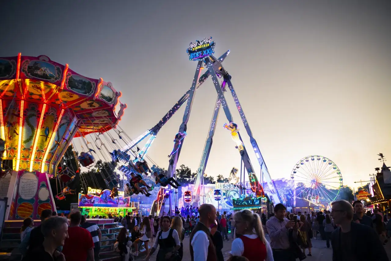 Buntes Treiben auf dem Volksfest Erding mit Karussells und Fahrgesch&auml;ften im Abendlicht.