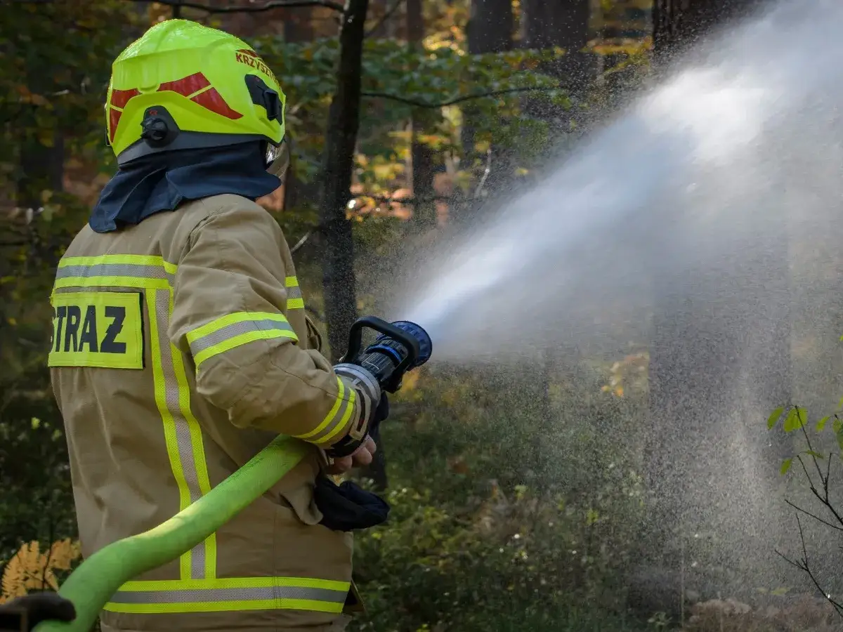 Strażak w akcji, gaszący pożar. Zastanawiasz się, ile zarabia strażak na start?