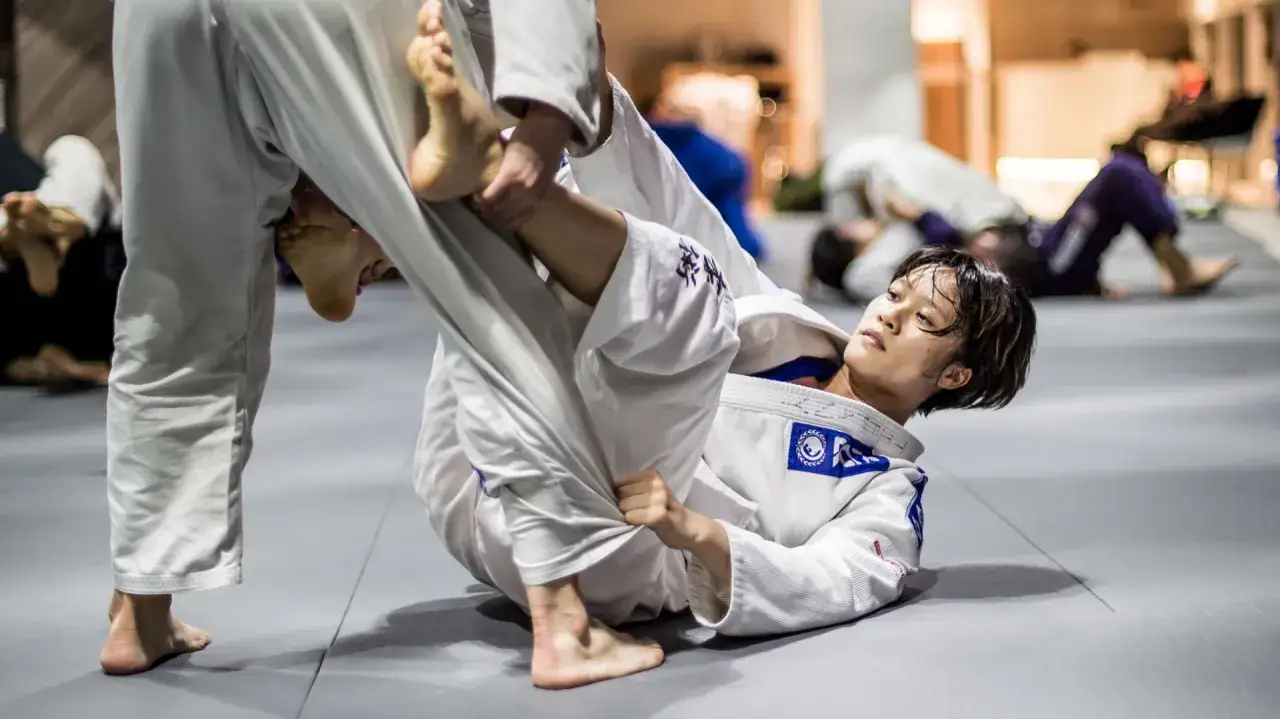 Deux pratiquants de jiu jitsu en action sur un tatami. L'un est au sol, l'autre tente une prise.