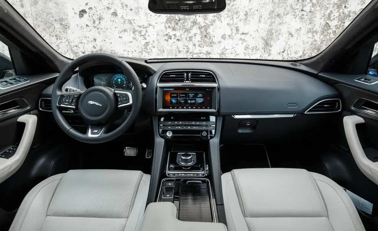 Wnętrze Jaguar F-Pace: jasna skóra, nowoczesny kokpit z ekranem dotykowym. Opinie o tym aucie często podkreślają komfort i technologię.