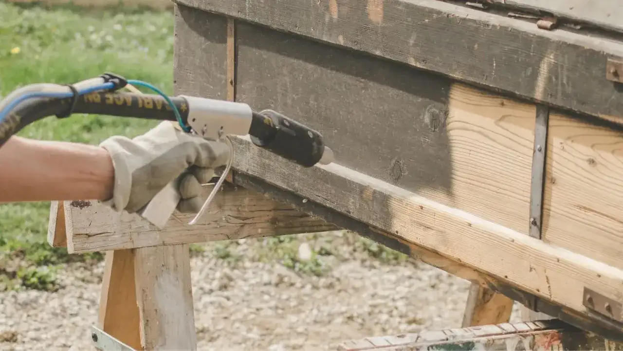 Utilisation d'un d&eacute;capeur thermique pour enlever la peinture sur du bois vieilli.
