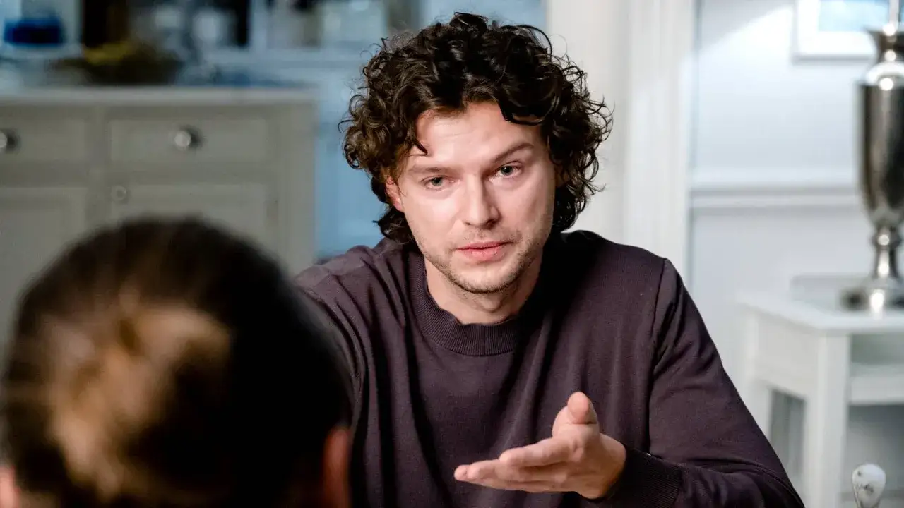 Mateusz Kościukiewicz w jednym z filmów, gestykuluje podczas rozmowy.