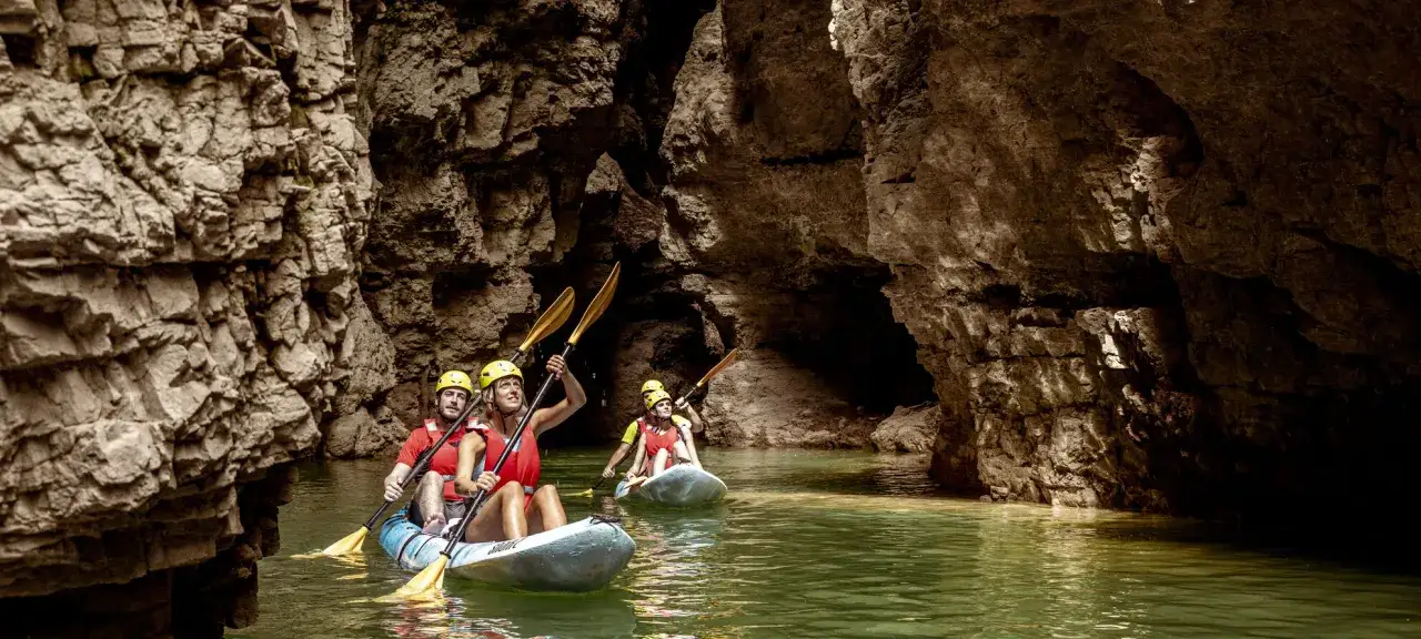 Kayakisti esplorano il suggestivo lago di Santa Giustina canyon, tra imponenti pareti rocciose.