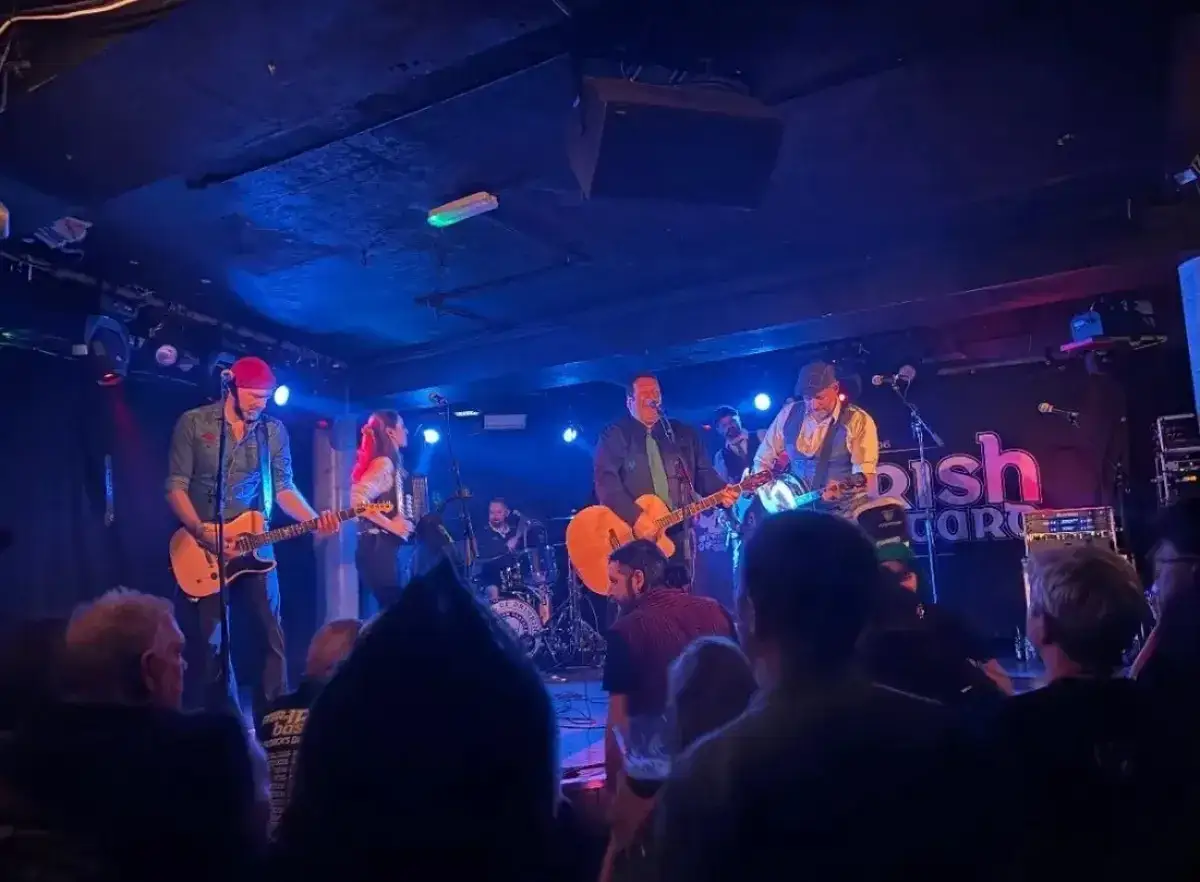 Un groupe irlandais punk enflamme la scène, guitares et accordéon résonnent sous les lumières bleues.