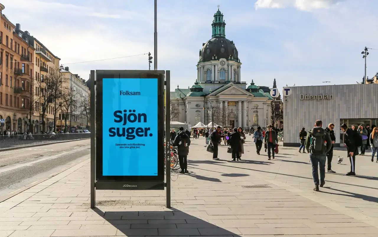 Folksam reklam på en blå skylt i en stadsmiljö.
