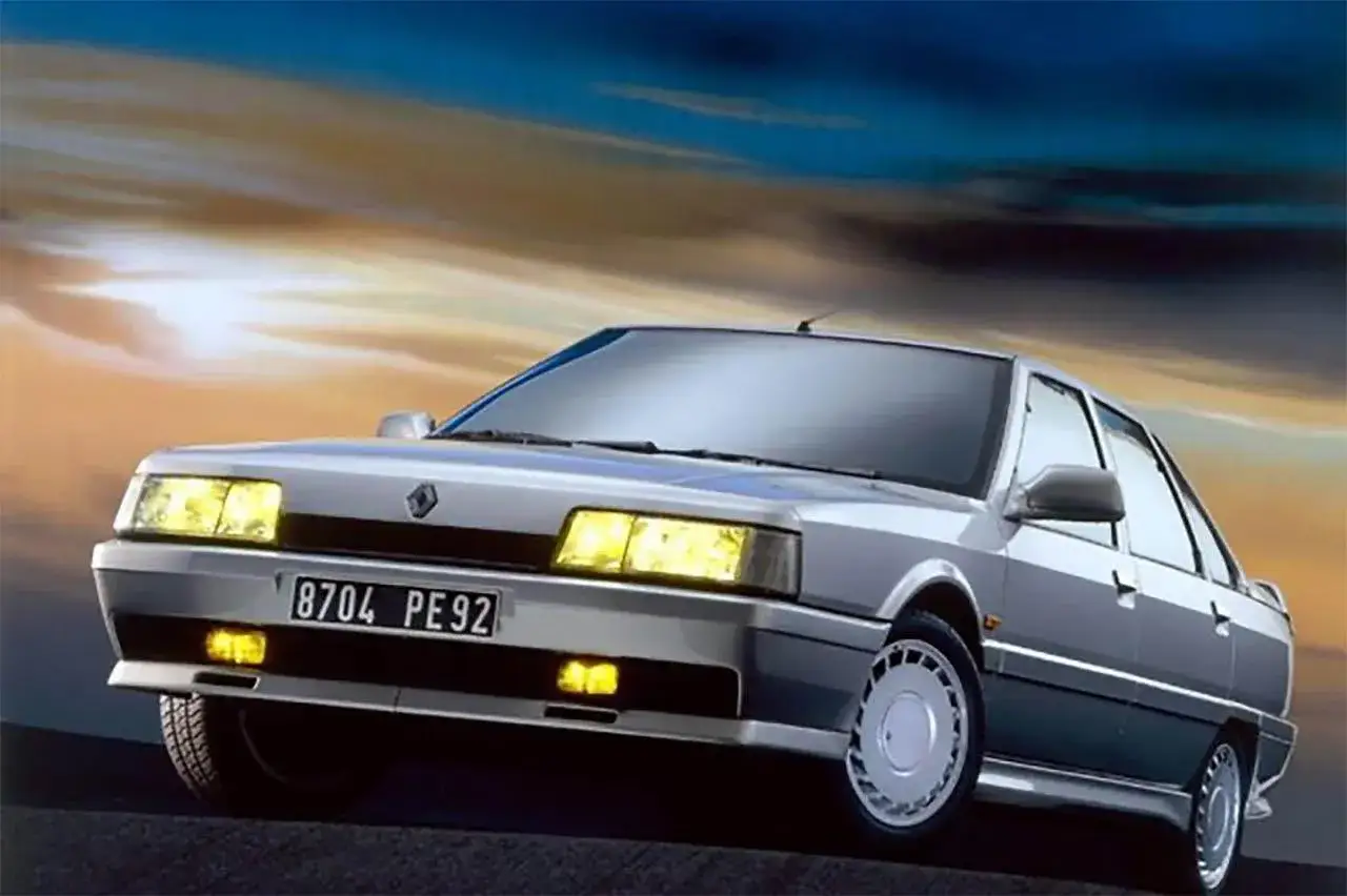 Srebrny Renault 21 z włączonymi światłami, na tle dramatycznego, zachodzącego słońca.
