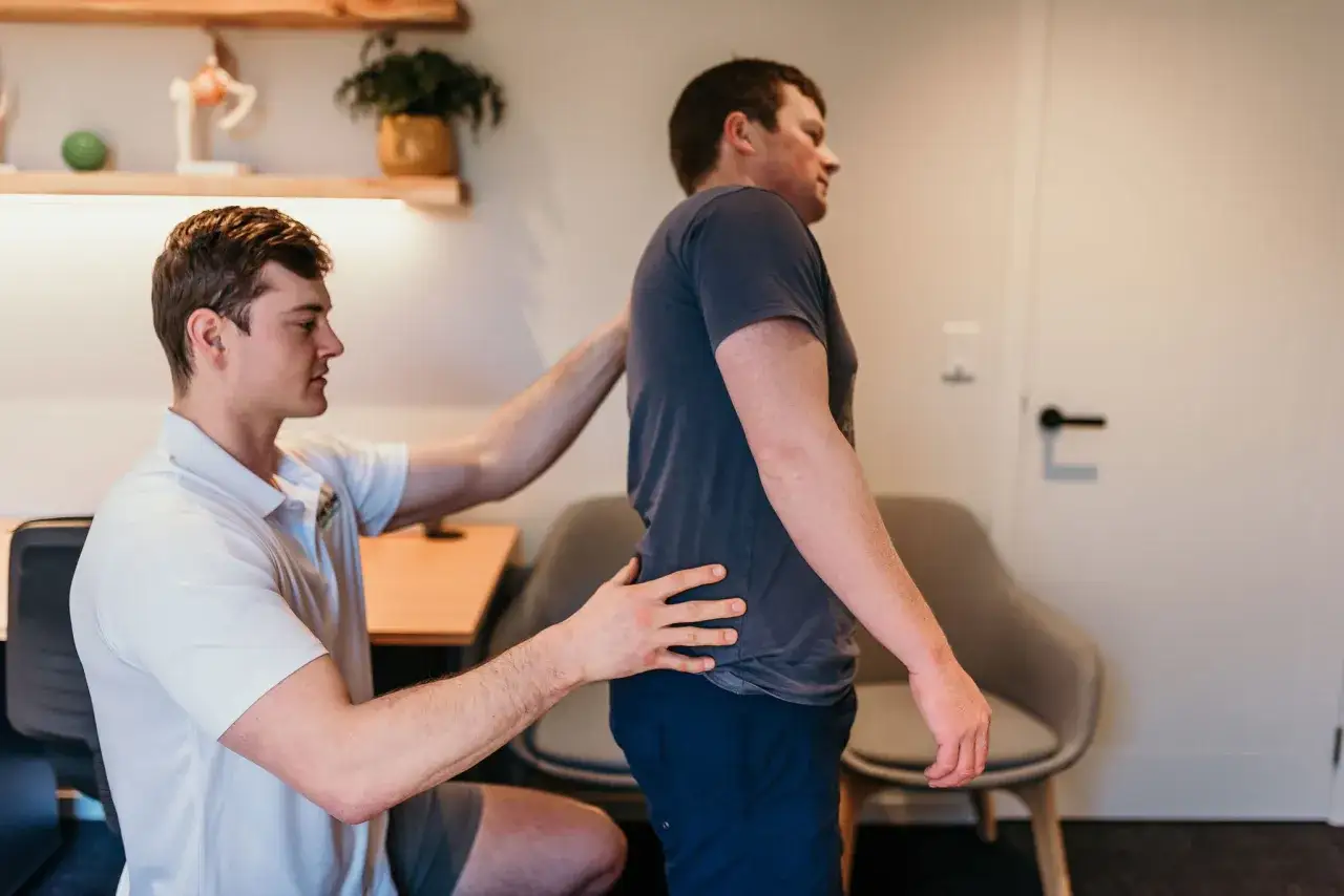 Osteopathie bei Verspannungen: Ein Therapeut untersucht den Rücken eines Mannes, um Schmerzen zu lindern.