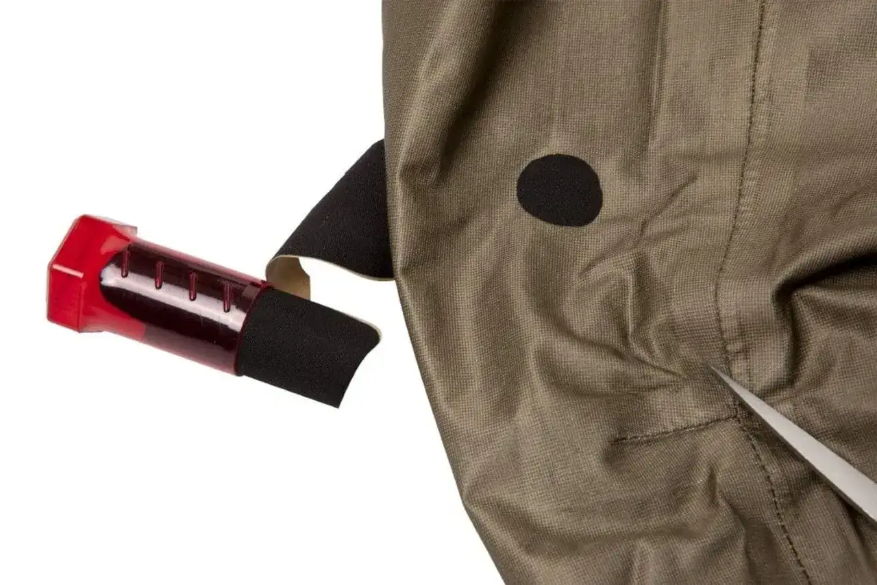 En röd behållare med svart tejp och en nål för att laga Gore-Tex.