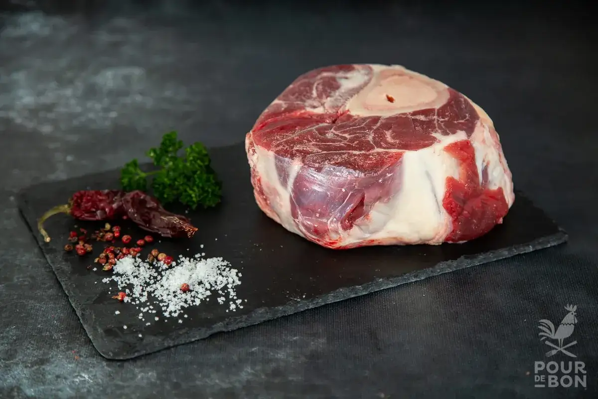Un beau jarret de boeuf cru, pr&ecirc;t &agrave; &ecirc;tre cuisin&eacute;, avec du persil, des piments s&eacute;ch&eacute;s et des grains de poivre.