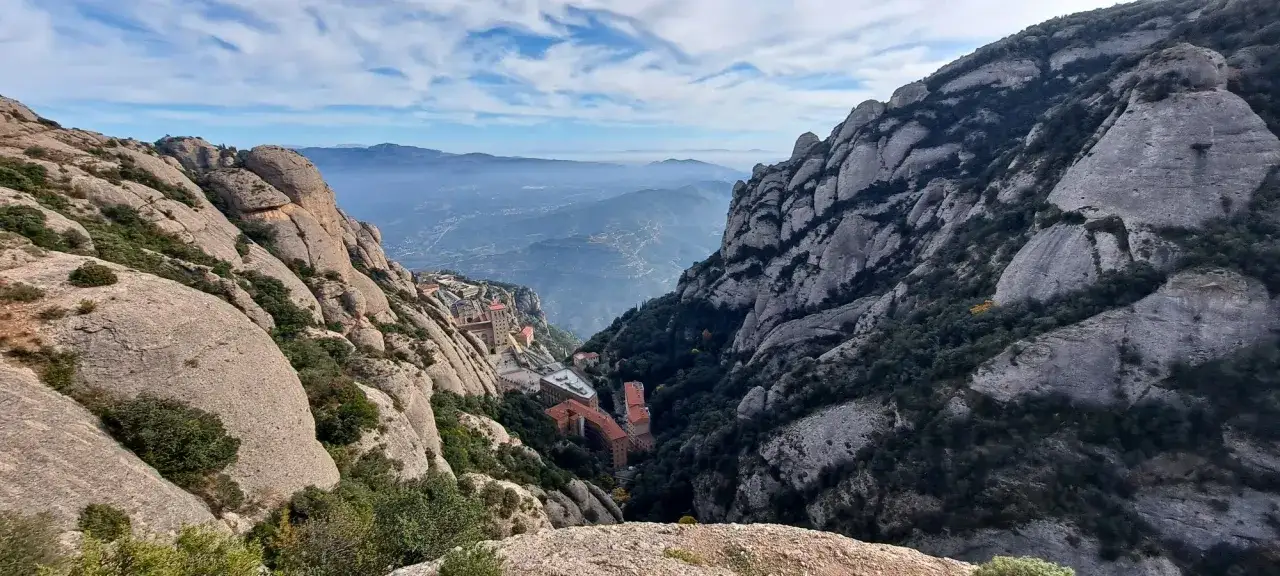 Vistas impresionantes de las rutas de Montserrat, con el monasterio encaramado en la montaña y un valle brumoso al fondo.