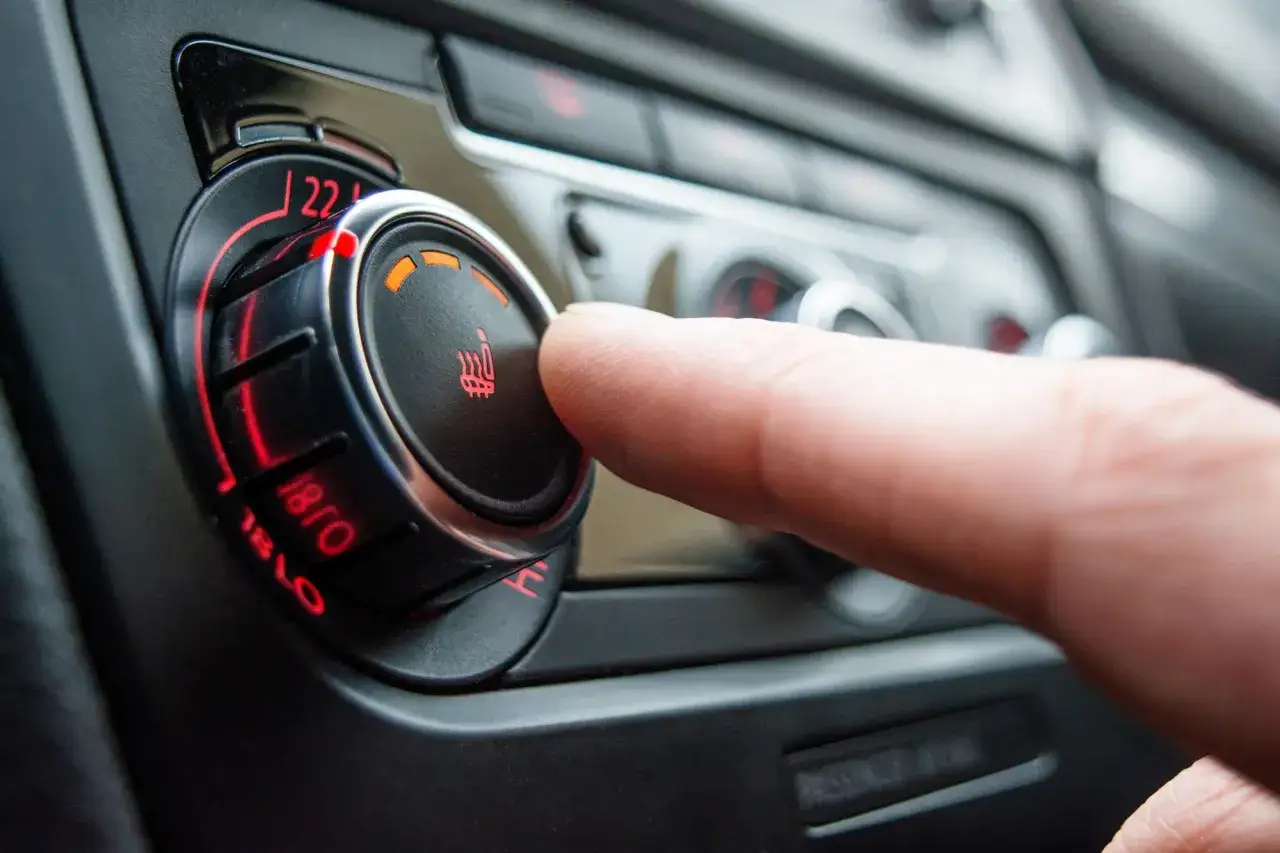 Dedo ajustando el control de temperatura del asiento, mostrando c&oacute;mo funciona la calefacci&oacute;n de un coche.