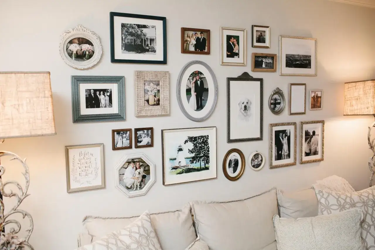 Un mur de cadres rempli de souvenirs : mariages, familles, un chien et un phare.