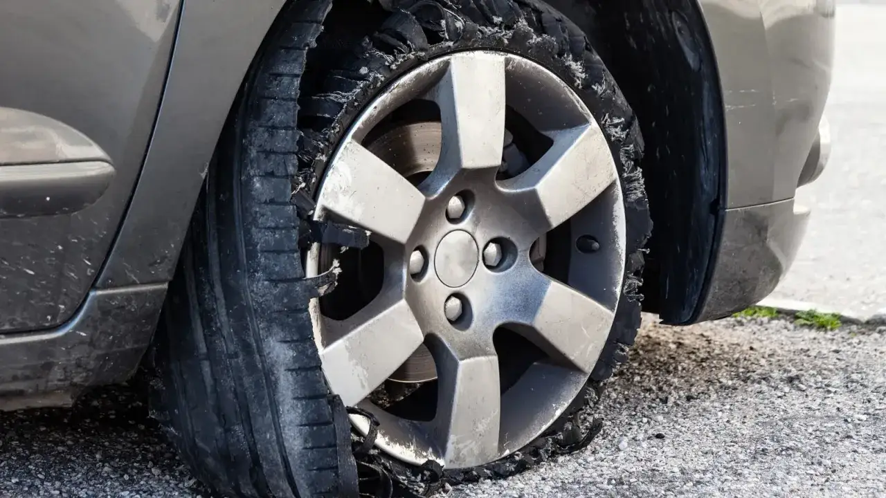 Ein Auto mit einem komplett zerst&ouml;rten Reifen. Die Frage, wie lange ein Auto auf einem platten Reifen stehen kann, wird hier eindrucksvoll beantwortet: nicht lange.