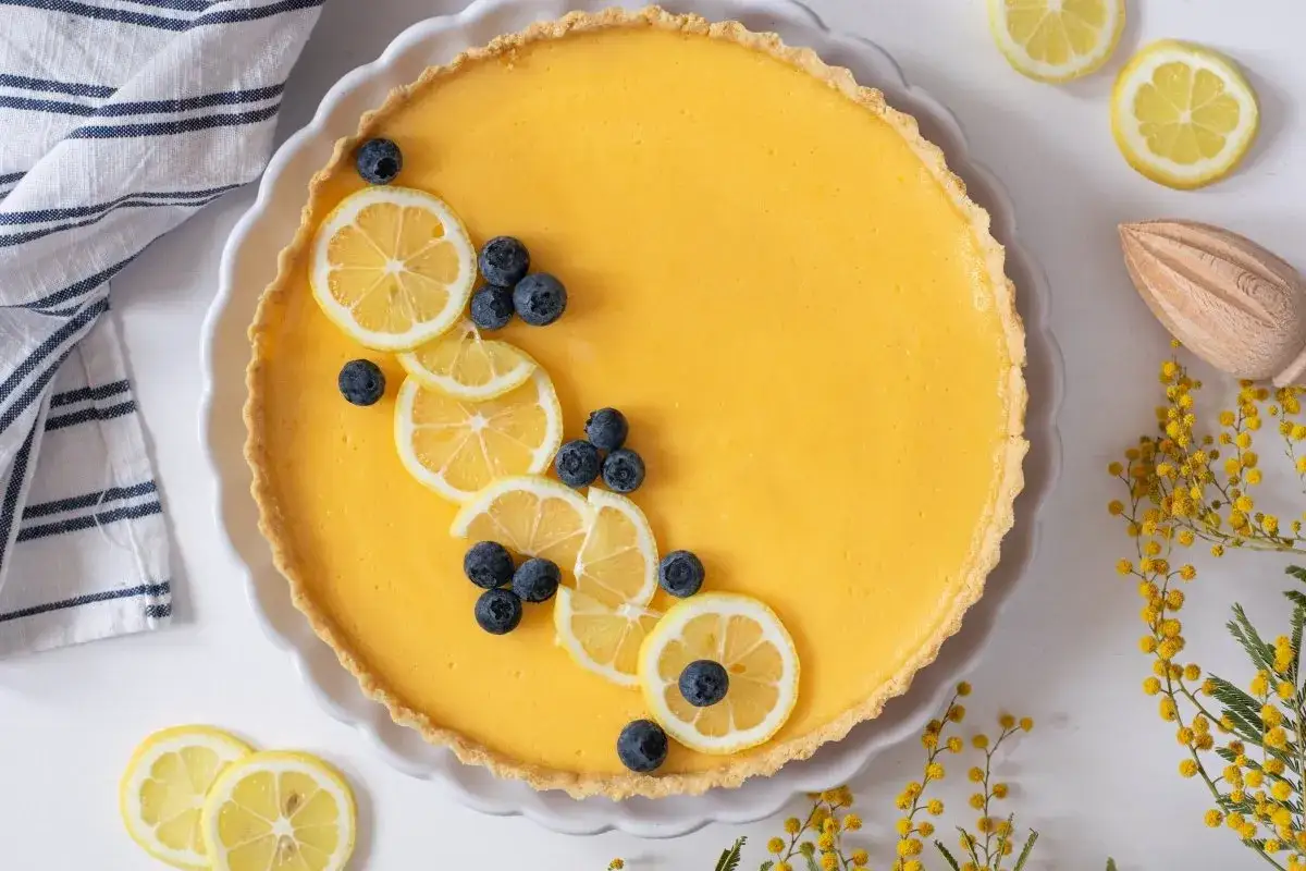 Tarta de limón con leche condensada, decorada con rodajas de limón y arándanos. Un postre refrescante y delicioso.