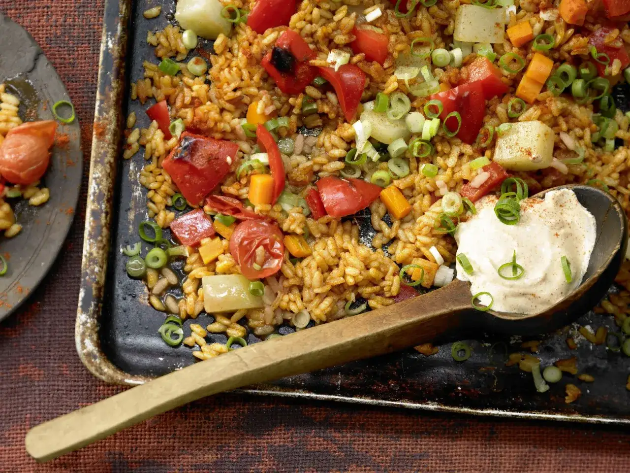 Leckere vegetarische Gerichte: Reis mit Paprika, Karotten und Fr&uuml;hlingszwiebeln, serviert mit einem Klecks Dip.