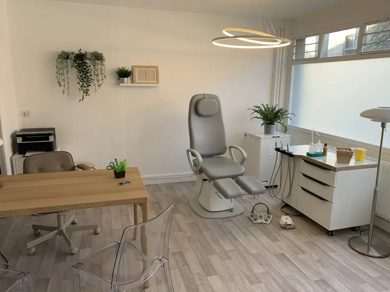 Cabinet de pédicurie moderne avec fauteuil, table, imprimante et plantes vertes.