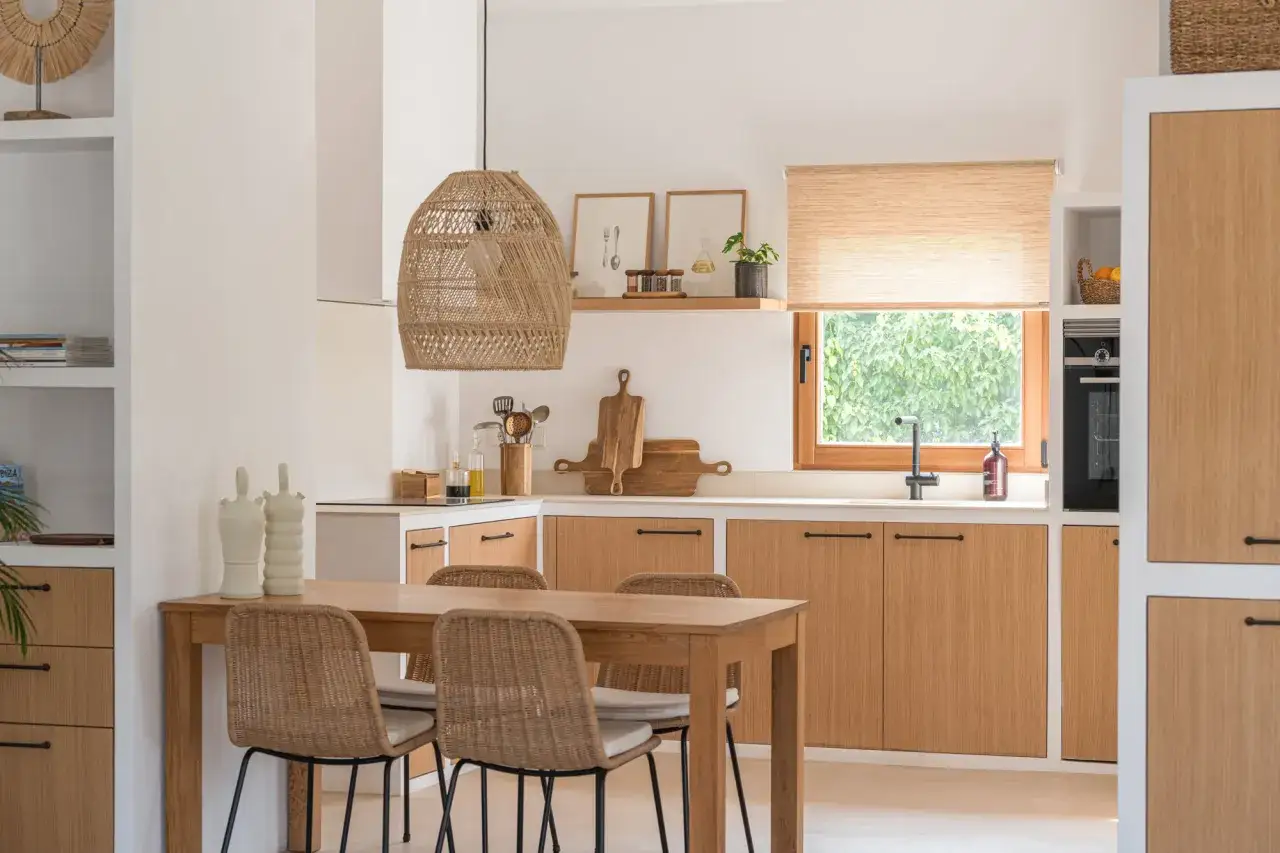 Mesa de cocina de madera con sillas de rat&aacute;n. La decoraci&oacute;n de la mesa incluye jarrones blancos y un centro de mesa r&uacute;stico.