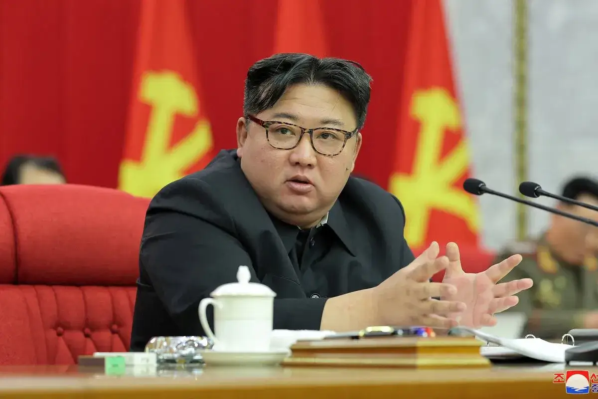 Prezydent Korei Północnej, Kim Dzong Un, w okularach, gestykuluje podczas spotkania.