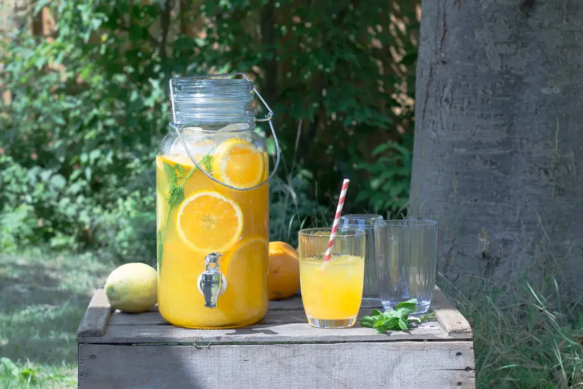 Erfrischende selbstgemachte Limonade mit Orangen und Minze in einem gro&szlig;en Glasbeh&auml;lter, bereit zum Servieren.