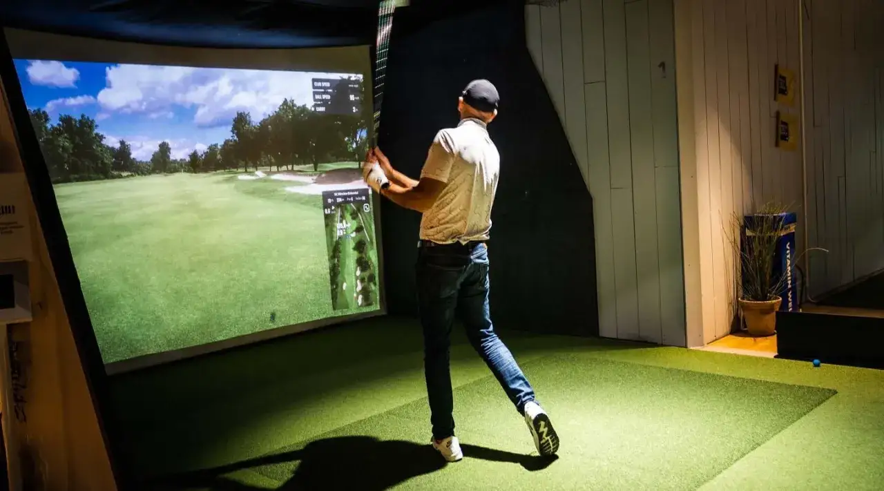 Man svingar golfklubba i en golfsimulator på Golfbaren Stockholm.