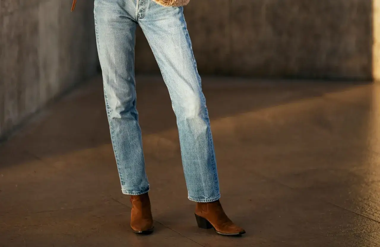 Un pantalon en jean bleu clair porté avec des bottines en daim marron. Un look décontracté et chic pour femme.