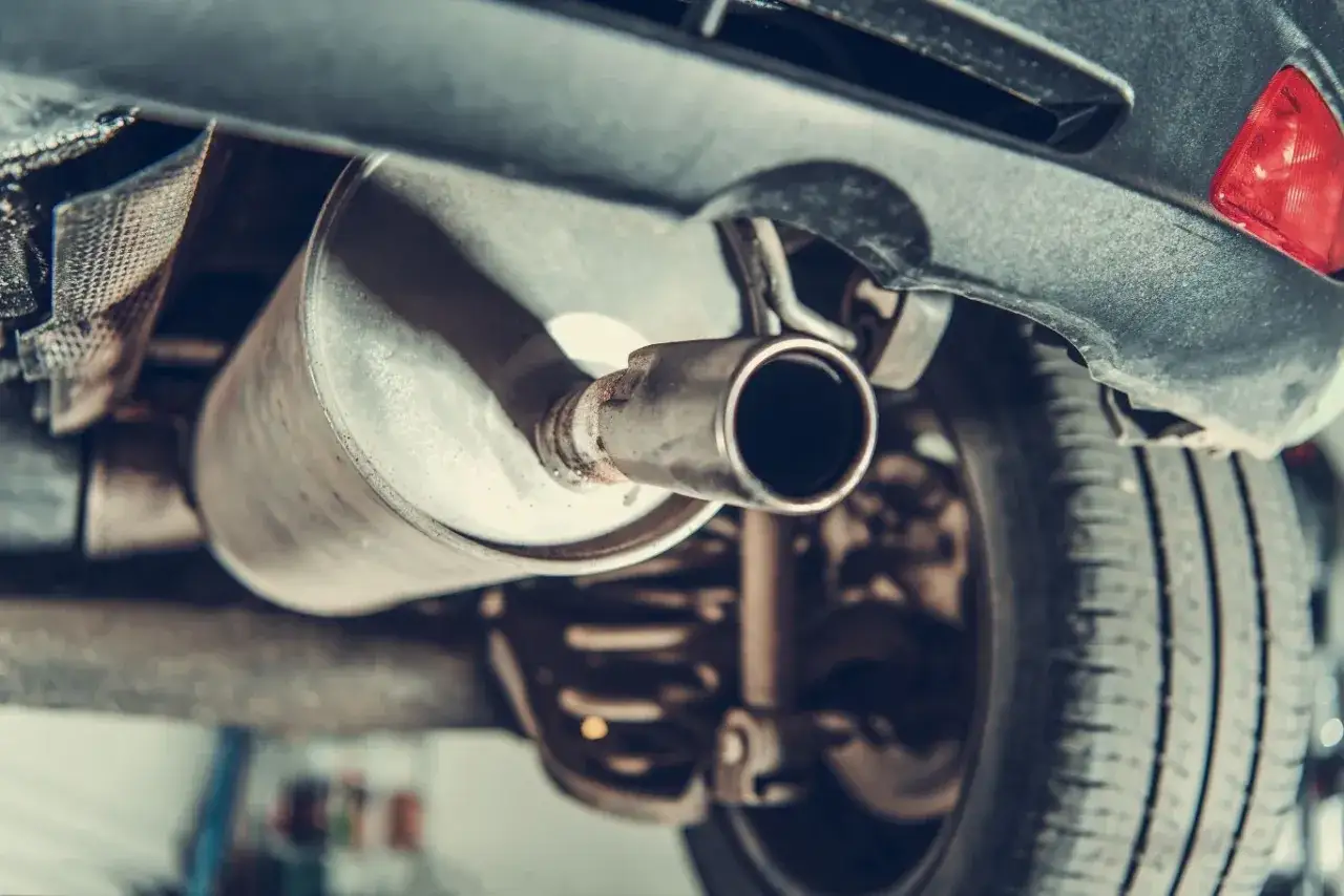 Podczas przeglądu podwozia, mechanik musi skontrolować układ wydechowy Renault. Widoczny jest tłumik i końcówka rury wydechowej.