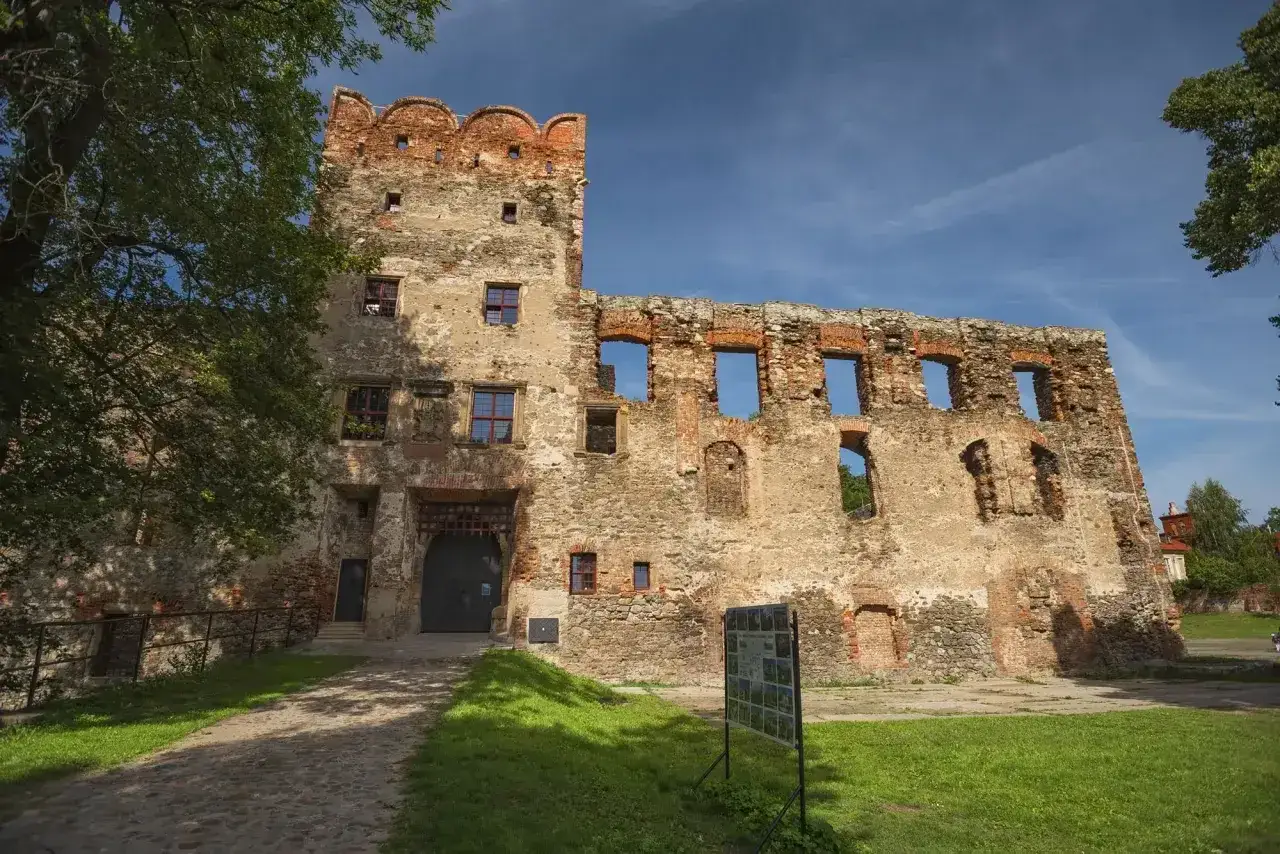 Kamienne mury i ceglane detale zamku w Ząbkowicach Śląskich, z widocznymi pustymi oknami i bramą, opowiadają historię.