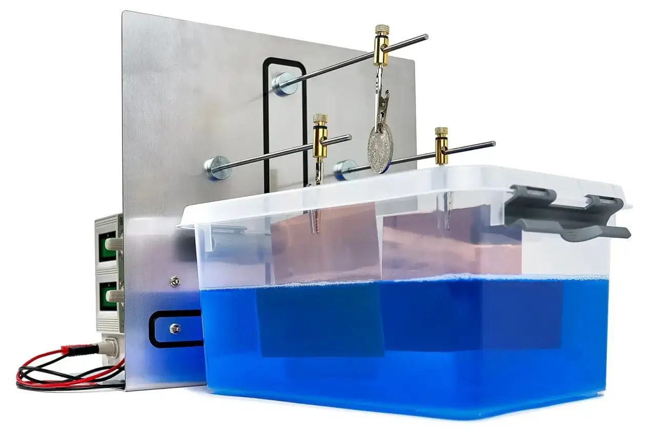 Apparecchio per galvanica con vasca blu e moneta appesa, ideale per trattare le leghe metalliche.