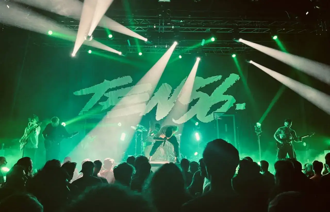 Scène de concert éclairée en vert, avec le logo 