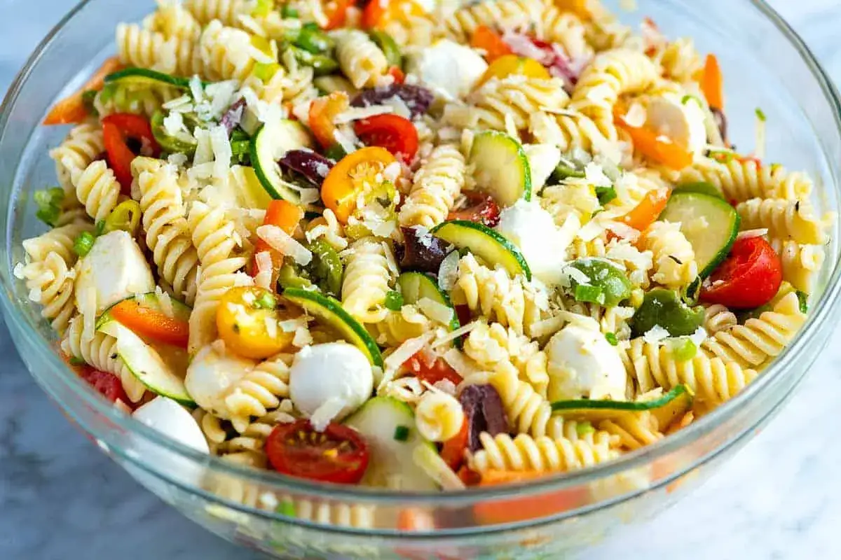 Kolorowa sałatka z makaronem fusilli, pomidorkami, cukinią, oliwkami i mozzarellą. Idealna sałatka z makaronem na szybko.
