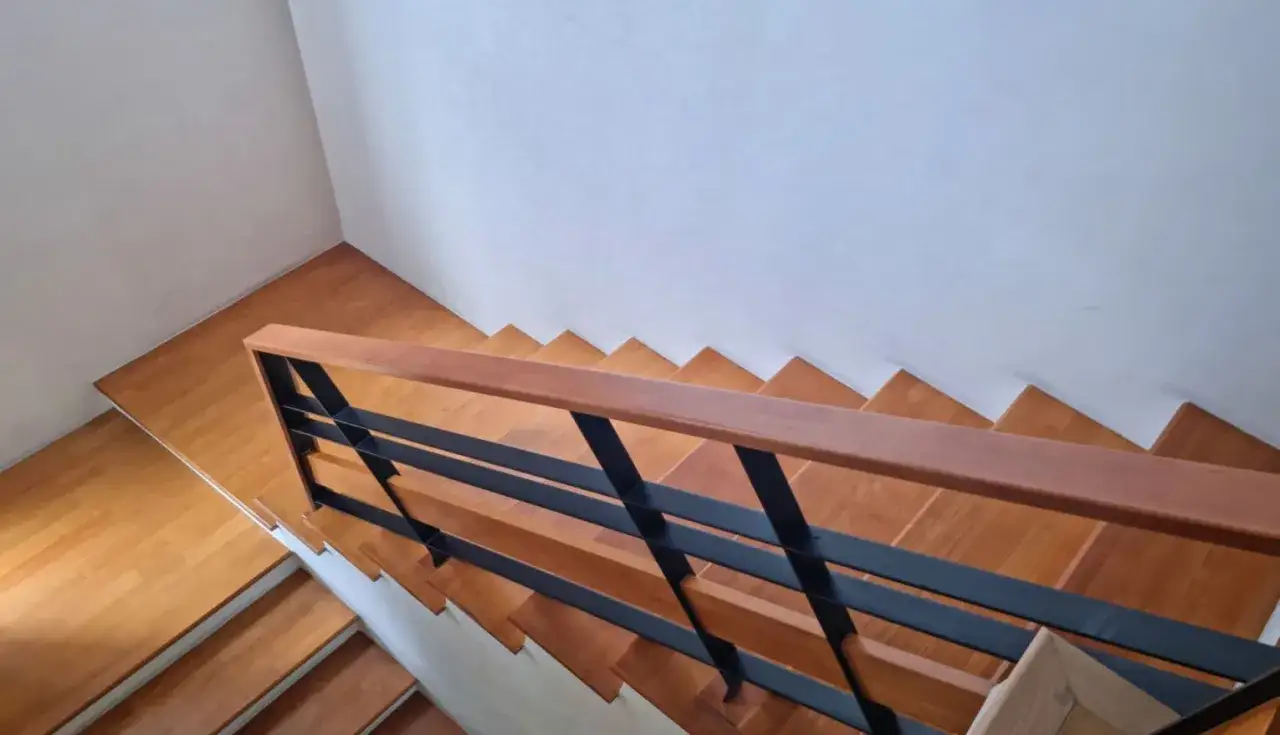 Barandilla de madera con dise&ntilde;o moderno, ideal para como modernizar una barandilla de madera. Escaleras de madera y pared blanca.