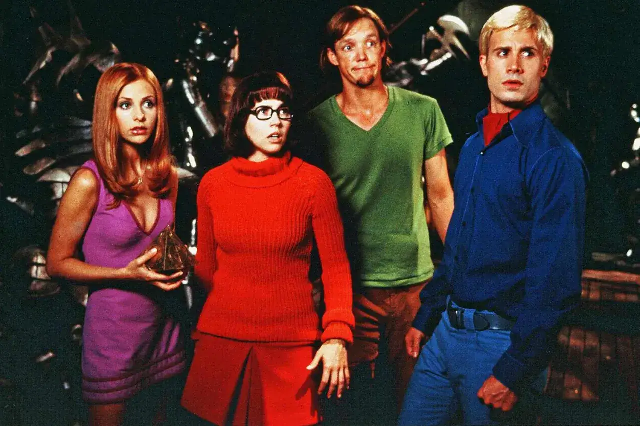 Obsada filmu Scooby-Doo: Daphne w fioletowej sukience, Velma w czerwonym swetrze, Shaggy w zielonej koszulce i Fred w niebieskiej koszuli.
