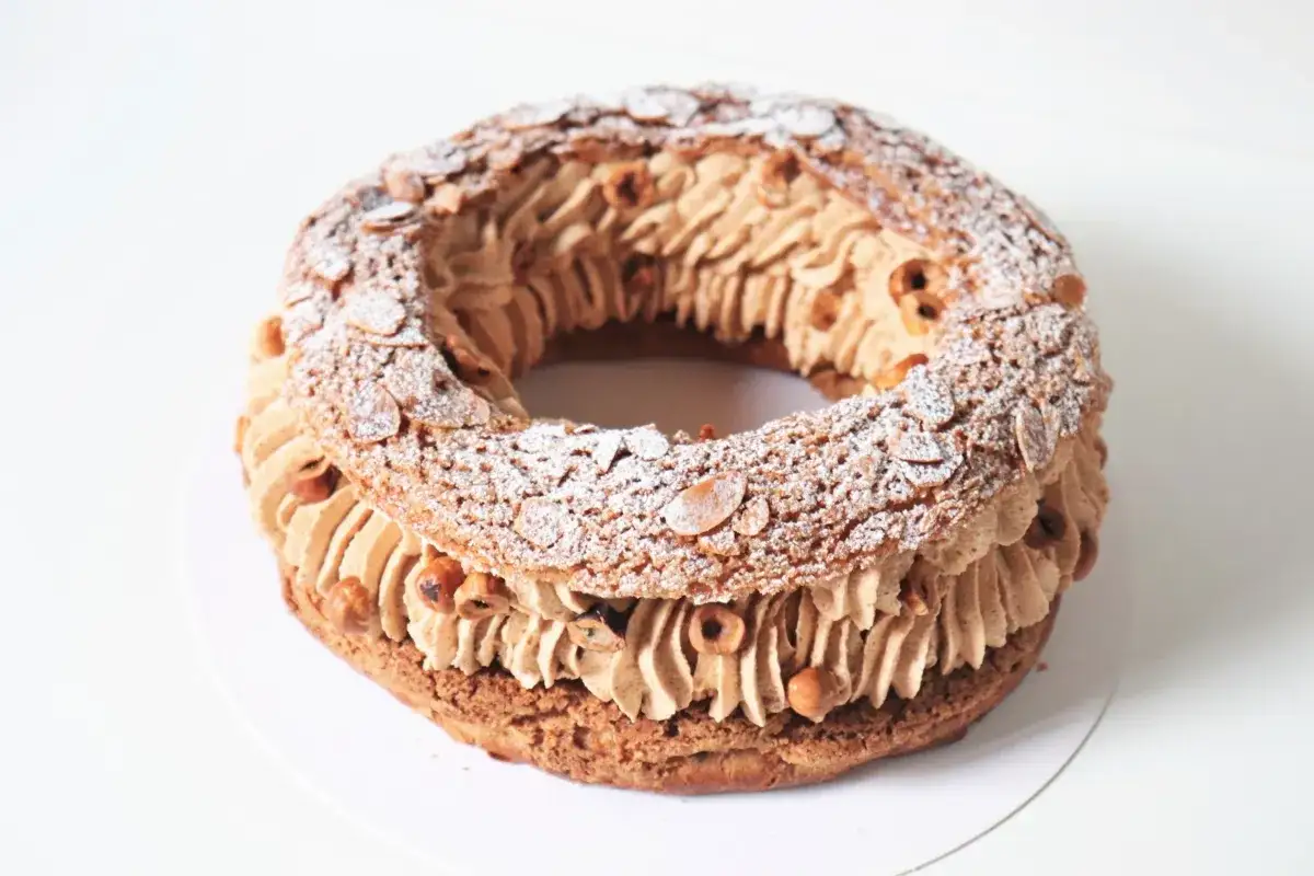 Un Paris-Brest gourmand, garni de crème pralinée et parsemé d'amandes effilées et de noisettes. Une recette qui fait rêver !