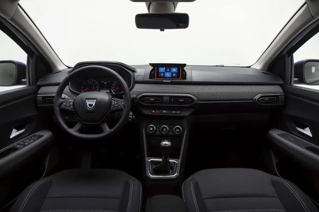 Wnętrze Dacia Sandero: kierownica, ekran multimedialny, dźwignia zmiany biegów. Wiele osób szuka dacia sandero opinie, by ocenić ten model.
