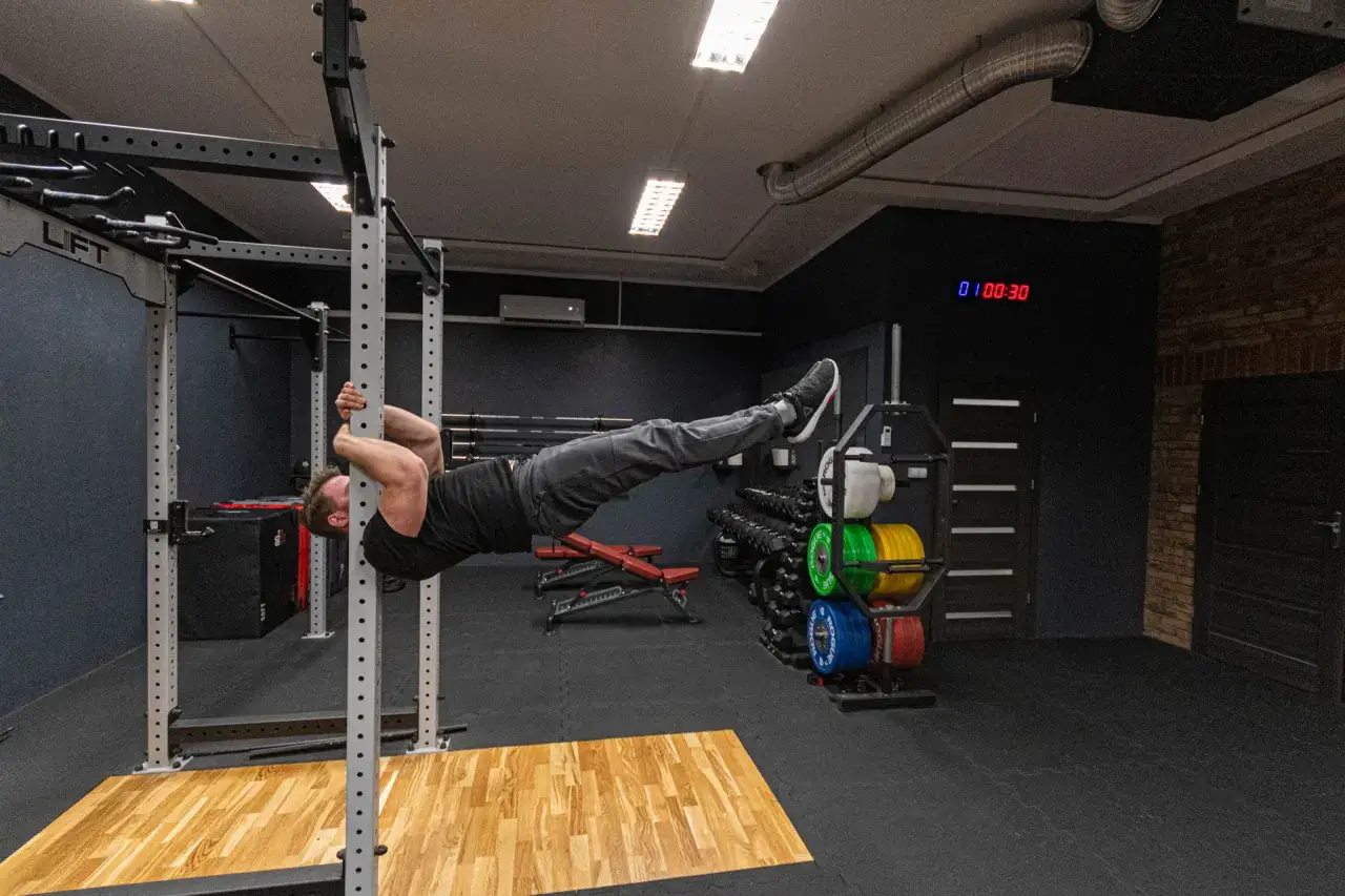Siła i kontrola: mężczyzna wykonuje planche na drążku. To dowód, że kalistenika czy crossfit to świetne wybory dla rozwoju ciała.