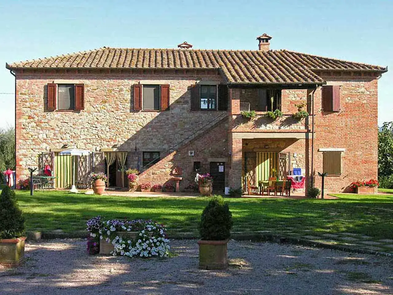 Un casale in pietra e mattoni, ideale per vacanze in Lombardia, con un giardino curato e fiori colorati.